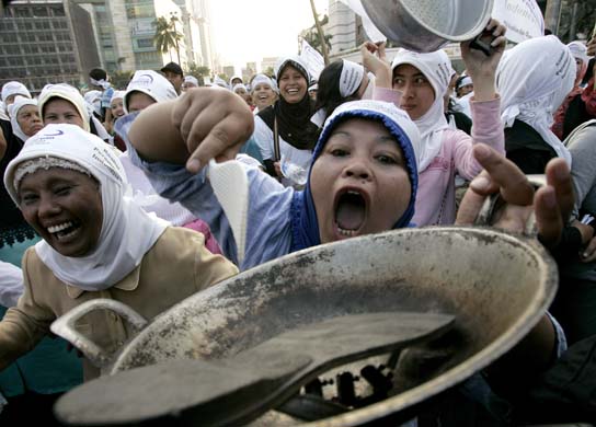 Women carry cooking utensils during a protest demanding that the government scrap the hike in fuel prices 