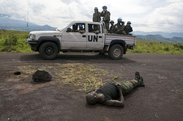 United Nations troops from MONUC pass the body of a Government soldier killed in fighting between Government forces and National Congress for the Defence of the People (CNDP) rebels