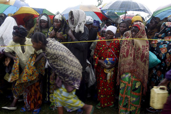 Displaced people run under a rope barrier, during a handout off emergency food rations in Kibati camp