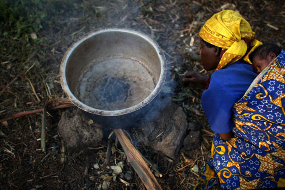 A woman lights a fire at a refugee camp in DR Congo