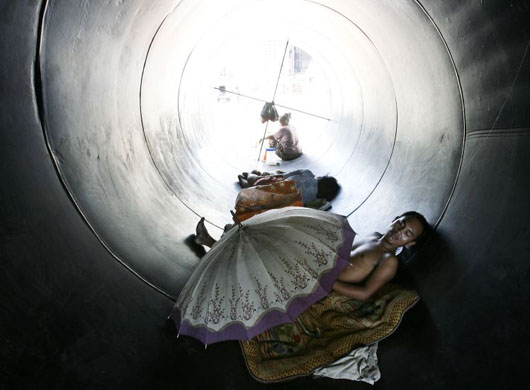 Manila, Philippines: A homeless man rests inside a water pipe
