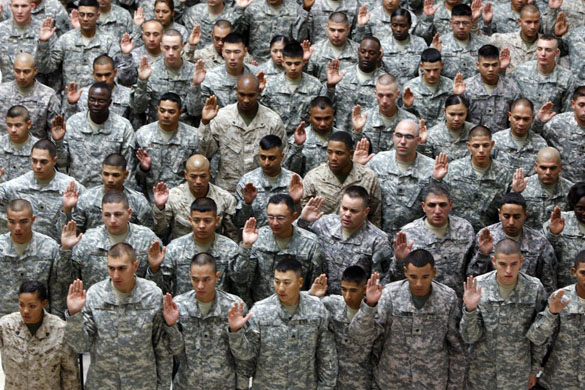 US soldiers hold their right hands up as they swear allegiance to the flag during a US Citizen Naturalization ceremony at Camp Victory