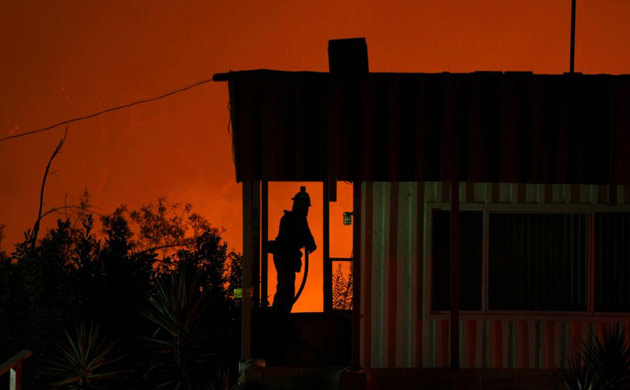 A firefighter protects a mobile home from a wild fire in Carbon Canyon near Brea, California