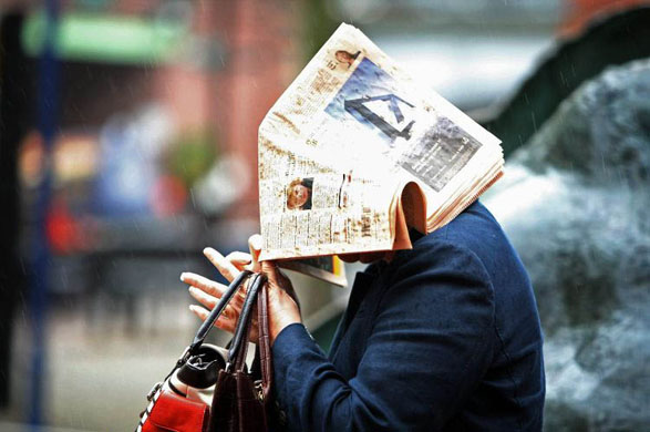 Birmingham, UK: A delegate uses a copy of the Financial Times to shield her from the rain