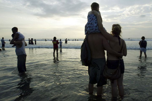Balil, Indonesia: An Australian family look at members of the Paddle for Peace Surf to remember victims who were killed by terrorist bombs in 2002