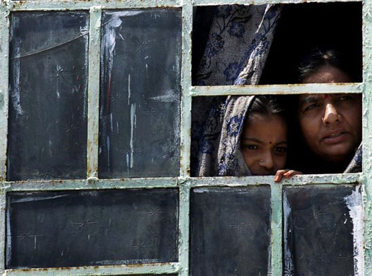 Bhainsa, India: Women look through the window of their home during curfew