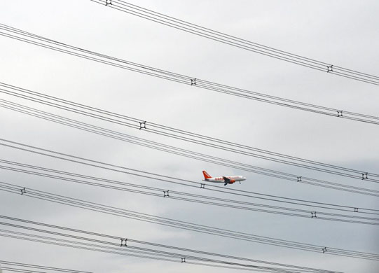 Ratcliffe on Soar, UK: An aircraft flies past electricity cables