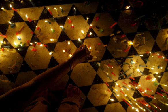 Amritsar city, India: A devotee lights candles along the holy pond of The Golden Temple, the most sacred place for Sikhs, on the occasion of 'Bandi Chorh' day