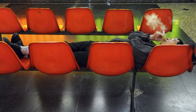 Chengdu, China: An investor smokes while resting on seats at a brokerage house