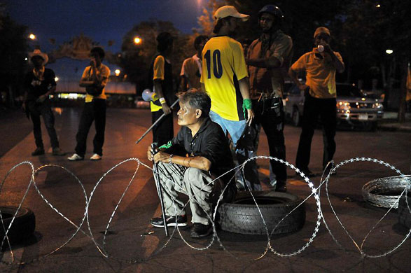 Bangkok, Thailand: An anti-government protestor blocks a street during a demonstration outside the Government House
