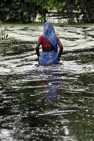 Kalabalua, India: A flood-affected woman moves to safer grounds