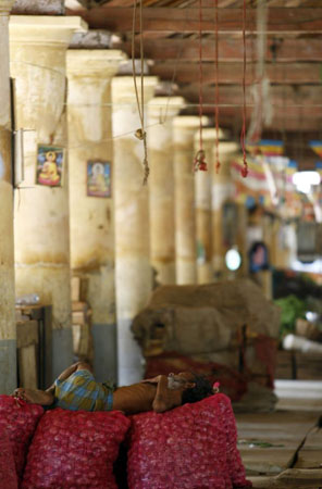 Galle, Sri Lanka: A labourer sleeps on bags of onions at a vegetable market