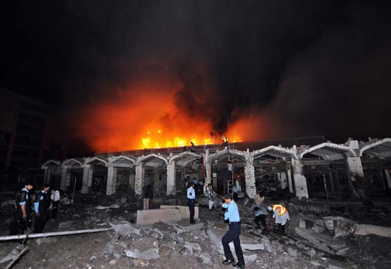 Pakistani policemen arrive outside the burning facade of the Marriott hotel