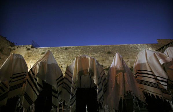 Jewish worshippers cover themselves with prayer shawls during morning prayers at the Western Wall