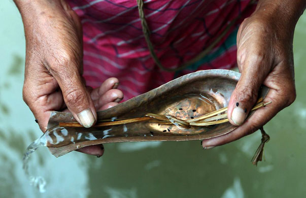 Kolkata, India: A man pours holy water from the river Ganges as part of a prayer ceremony during the holy day of Mahalaya