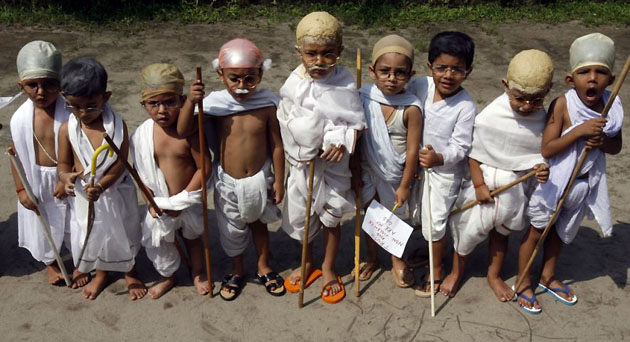 Siliguri, India: Children dressed as Mahatma Gandhi wait for their turn to perform during a fancy dress competition ahead of his 139th birth anniversary