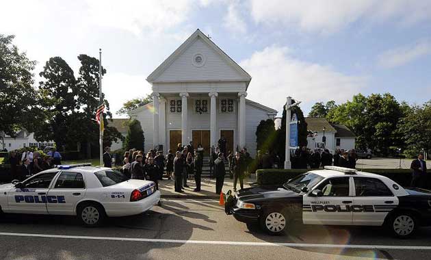 Police vehicles sit in front of St Francis Xavier church as participants begin to gather