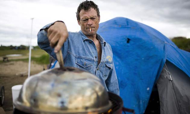Casey Riley heats water for coffee outside a tent