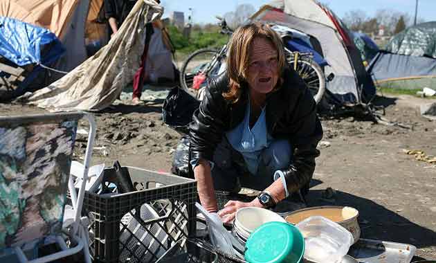 Carol Carlile washes dishes outside her tent