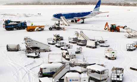 A plane and airport vehicles are covered in snow