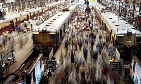 PASSENGERS WALK ON PLATFORMS AT A RAILWAY STATION IN BOMBAY.