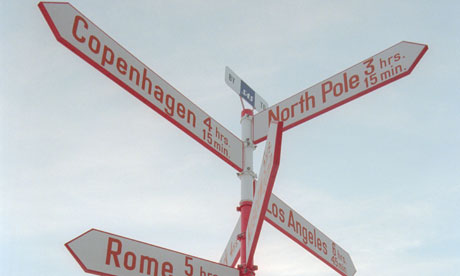 Greenland Tourist reading a guide book under a distance indicator sign