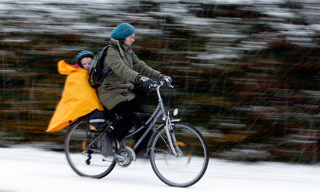 A woman and child cycle during a snow shower in Loughborough