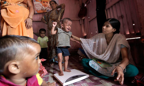 A boy is weighed in India: