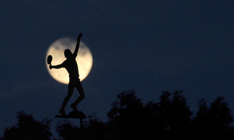 The moon rises behind a weather vane