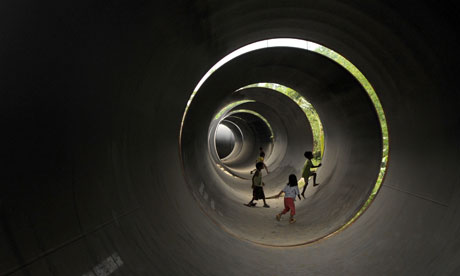 Children play inside steel pipes that wi