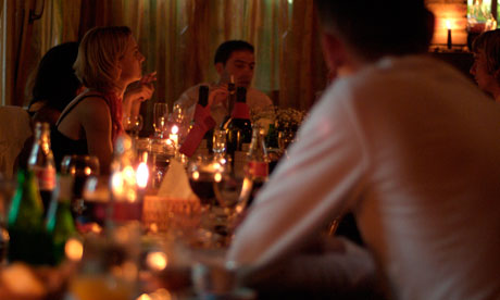 People Sitting Around a Candlelit Dining Table Enjoying Food and Drink