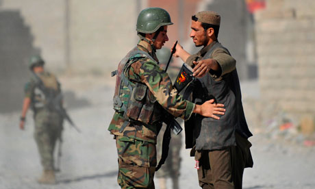 A soldier of the Afghanistan National Army checks a villager during a patrol in Helmand Province