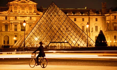 A lady on a bike outside the Louvre in Paris