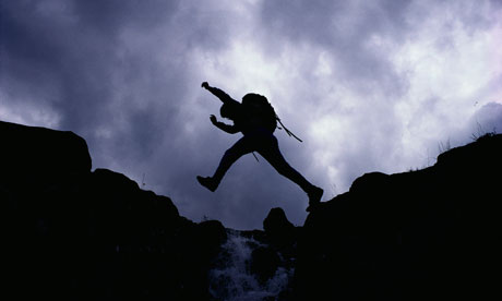 Hiker Jumping over Mountain Stream