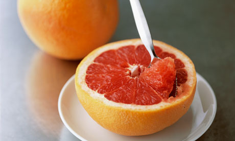 Half grapefruit with spoon and whole grapefruit