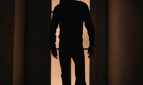 A man looking out through his curtains