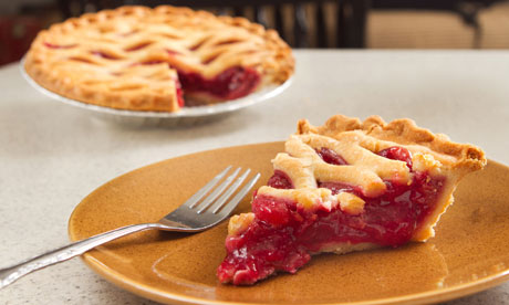 slice of cherry pie removed from a whole pie on a table