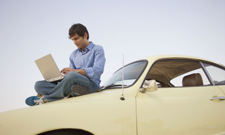 Man using laptop on top of car