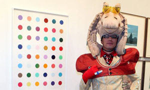 A visitor poses near a Damien Hirst piece at the Nitsch/Paragon gallery at Art Basel Miami Beach