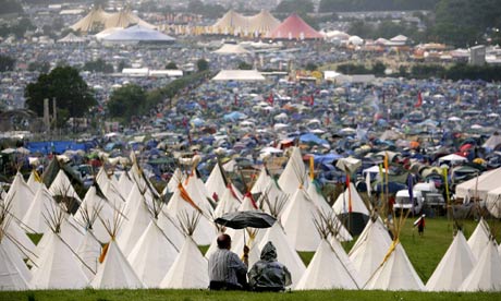 Fans shelter from rain at Glastonbury