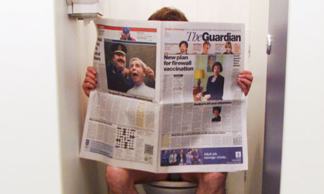 A man sitting on the toilet reading a newspaper