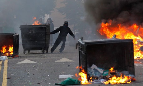 Rioters drag rubbish containers towards a burning car in Hackney, London
