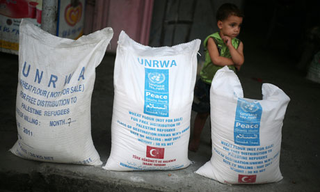 A Palestinians boy stands beside bags of food aid at a UN distribution centre in the Gaza Strip