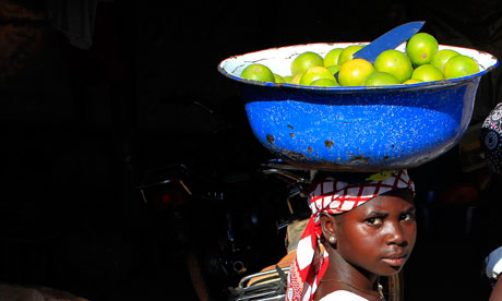 A woman carrying a bowl of fruit to market in a village near Abuja