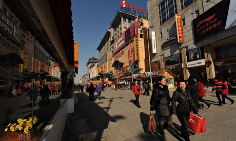 Shoppers walk through a busy retail street in Beijing