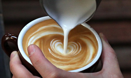 A barista pouring milk into a coffee
