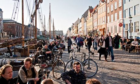 People sitting at along the waterfront of Nyhavn Canal, Copenhagen, Denmark