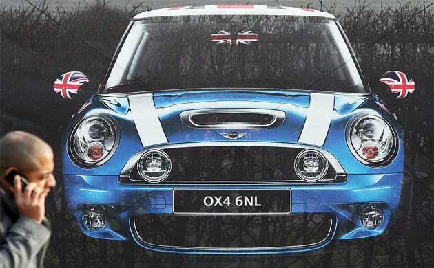 A man walks past a Mini sign at the BMW car plant in Cowley, Oxford