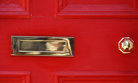 A red front door with a gold letterbox and door knob