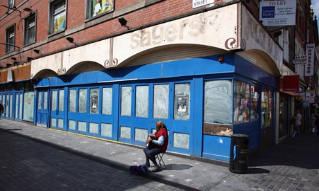 A busker plays outside a closed down shop in Liverpool